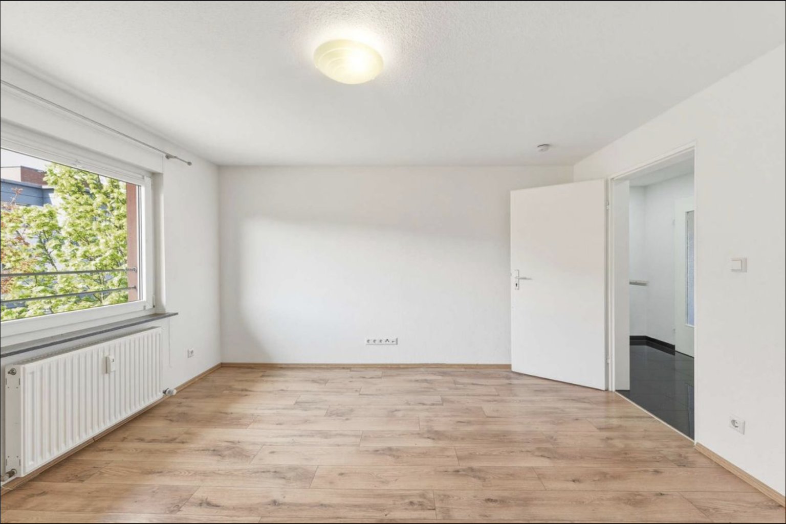 Bild einer weißen leeren Wohnung mit einem Fenster ins Grüne